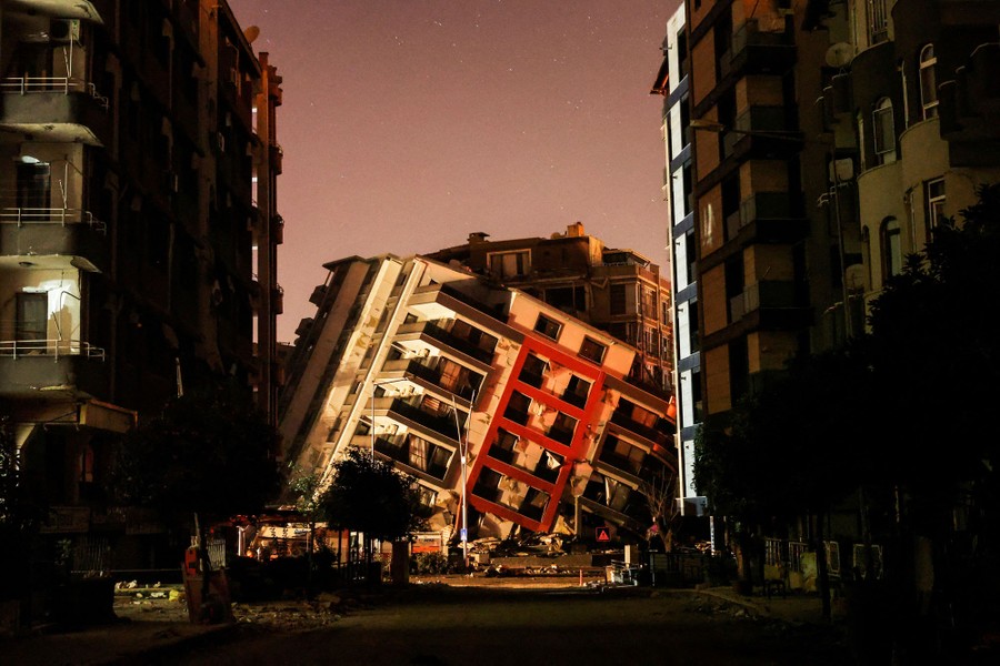A street view of a partially collapsed building resting at a sharp angle