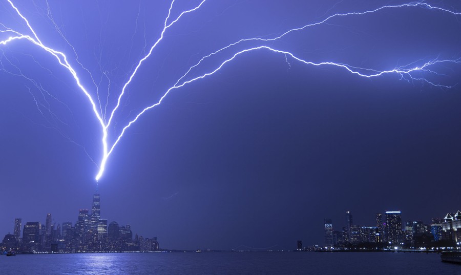 Lightning bolts arc across a dark sky as they strike One World Trade Center in New York City.