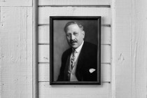 A black-and-white photo of a portrait of a man wearing glasses and a suit.
