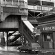 black-and-white photo of Boston's Washington Street Elevated in the 1980s with Dover station exit, diner with "Luncheon" neon sign, wood-paneled station wagon