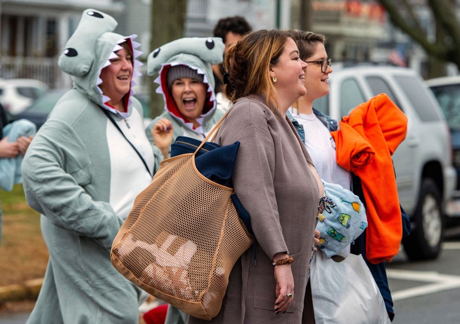 Several people, two of them wearing shark costumes, cross a street.