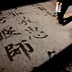 A man writes Chinese characters on a footpath using water and a brush in central Beijing.