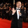 Harvey Weinstein poses on the red carpet with photographers behind him.