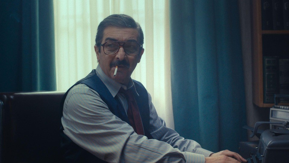 A still from Argentina, 1985, featuring a lawyer wearing big glasses and smoking a cigarette