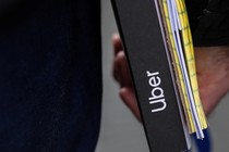 A close-up of a man carrying an Uber-branded binder