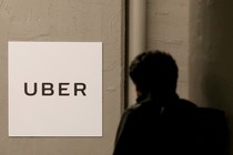 A person walking past a wall with an Uber sign on it