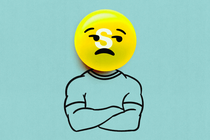 A man with his arms crossed and a sad-faced yellow skittle for a head