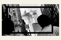 A black-and-white image of the back of two people's heads as they watch smoke coming out of the World Trade Center's Twin Towers during 9/11