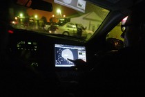 A person points at a GPS inside a vehicle on a residential street.