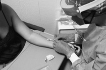 a masked healthcare worker injects a monkeypox vaccine intradermally into a woman's arm. the needle is entering almost horizontal to the arm so it can be shallow.