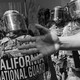 A photograph of the California National Guard, with a hand reaching in front of the camera lens