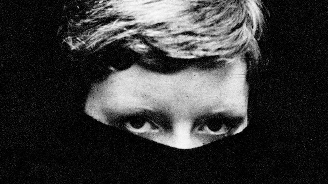A black-and-white photo of a person with the bottom half of their face covered