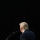 photo of Donald Trump's back at a microphone surrounded by black