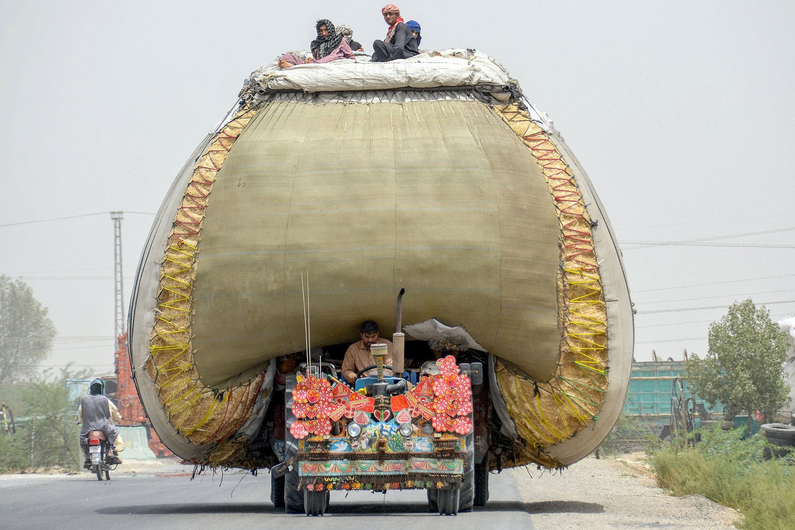 Farmers transport wheat straw loaded on a heavily-loaded tractor.