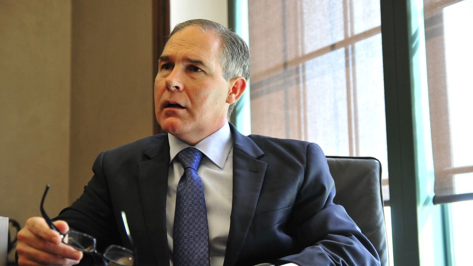 Scott Pruitt holds his glasses and looks out of the frame, with an upset expression on his face.