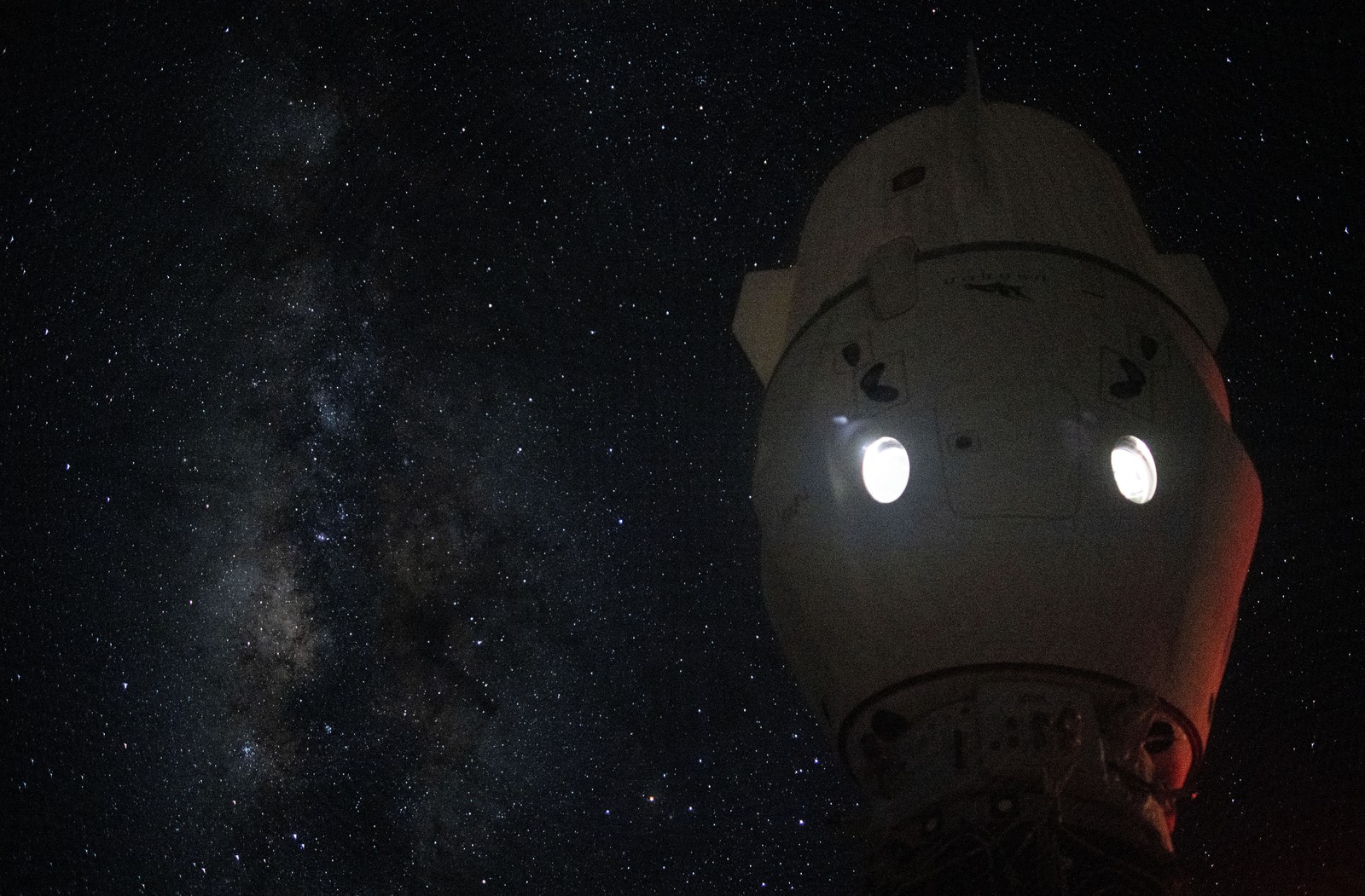 The Milky Way appears in the vastness of space behind a docked spacecraft.