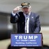 Republican presidential candidate Donald Trump gestures to a his camouflaged "Make America Great" hat at a campaign rally at the Redding Municipal Airport in Redding, Calif.