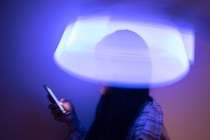 An Asian girl looks at her phone screen with a blurry light distortion around her head