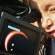 A boy watches an annular eclipse through a camera.