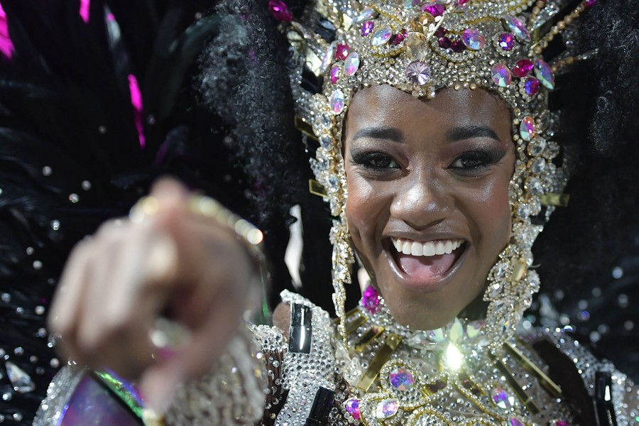 A performer in costume smiles and points toward the camera.