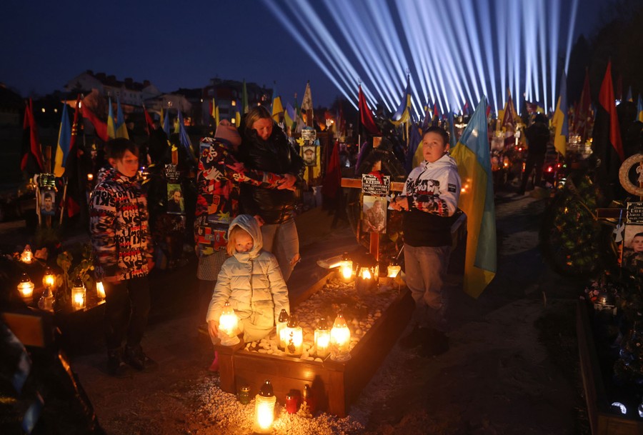 Family members gather in a cemetery beneath beams of light.