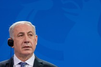 Israeli Prime Minister Benjamin Netanyahu appears in the lower left of the frame, in front of a blue background