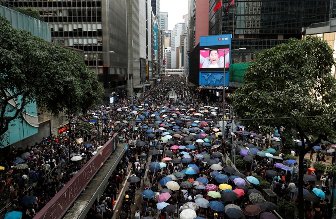 Protesters holding colorful opened umbrellas march down a Hong Kong street.