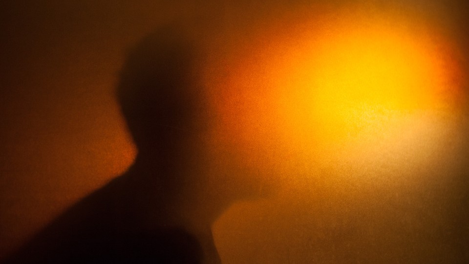 A silhouette with the face blurred out by a bright orange light