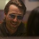 Glen Powell wearing aviator sunglasses and smiling