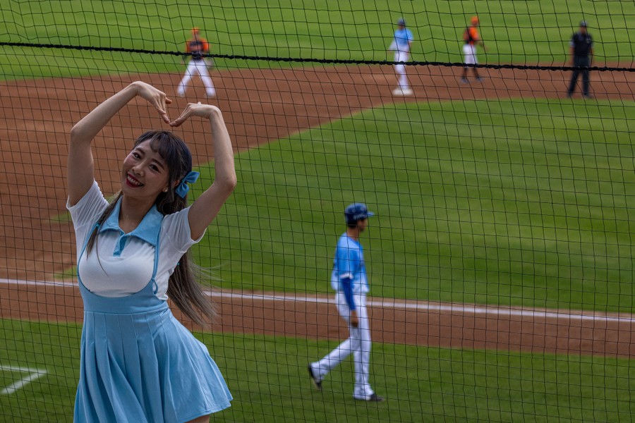 A cheerleader performs in front of fans at a baseball game.