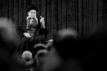 Iran's Supreme Leader Ali Khamenei speaks on a stage, gesturing with his left hand.