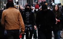 Masked and unmasked people, walking down a city street