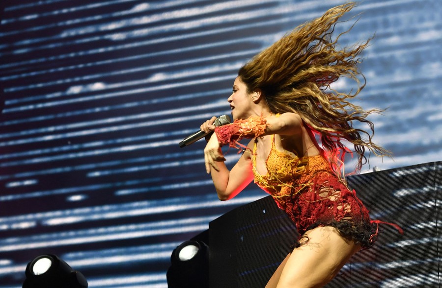 Wind blows the long hair and costume of a singer as they perform onstage.