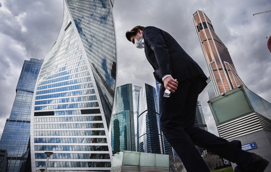 Photos of the Week: Desert Highway, Launch Symphony, Mermaid Show A man walks near distinctive skyscrapers.