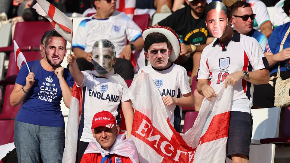 England fans wear masks of players and hold up an English flag