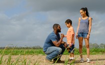 Ralph Angel Bordelon, Darla, and their son Blue, in a brown and green field with a blue gray sky in the background