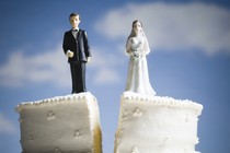 A wedding cake split in two, separating the figurines of the husband and wife