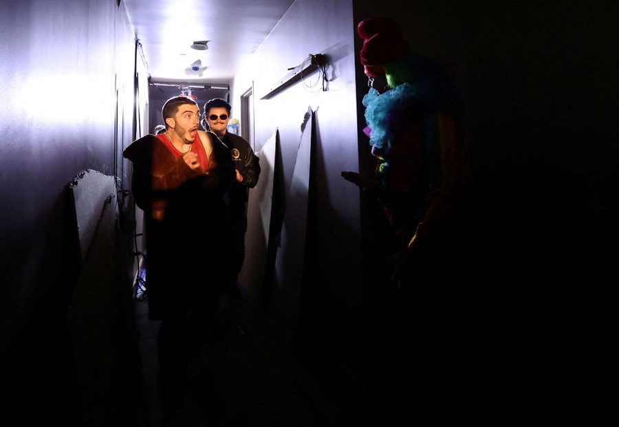 Two people in a dark hallway are scared by a person in costume.