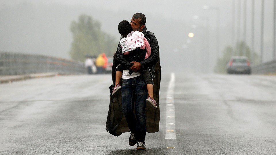 A Syrian refugee carries his daughter in Greece as he approaches the Greek-Macedonian border in September 2015.