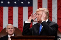 President Donald Trump raises his hands to his head while delivering his first State of the Union address.