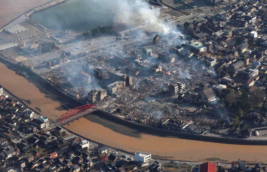 An aerial view of a ruined district along a canal, following an earthquake
