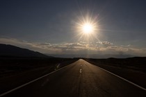 Photo of a low sun above a long road