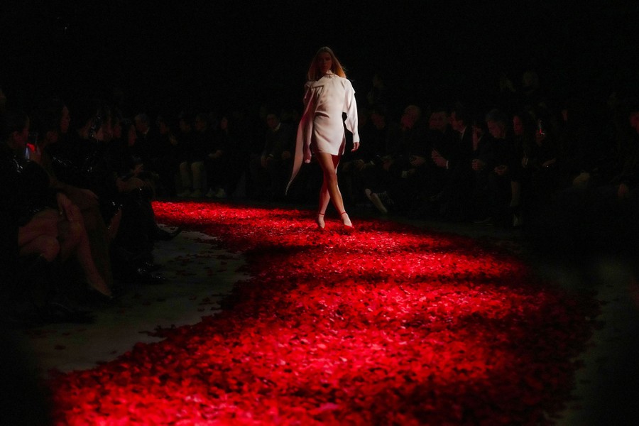 A model walks down a runway covered in red flower petals.