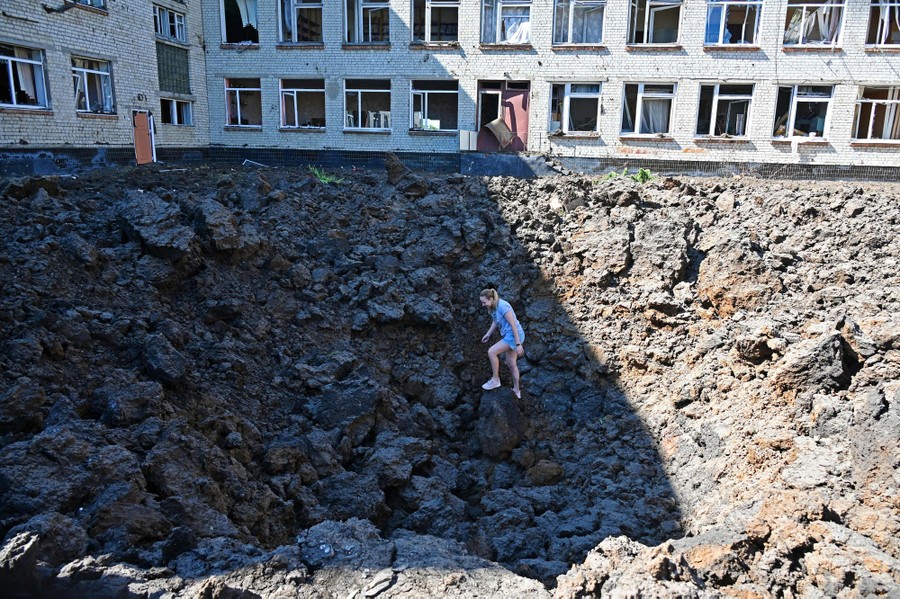 A woman stands in a deep crater in a schoolyard.