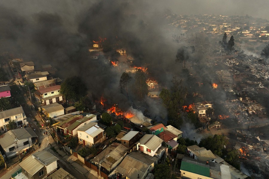 An aerial view of a hillside residential neighborhood with many burning houses