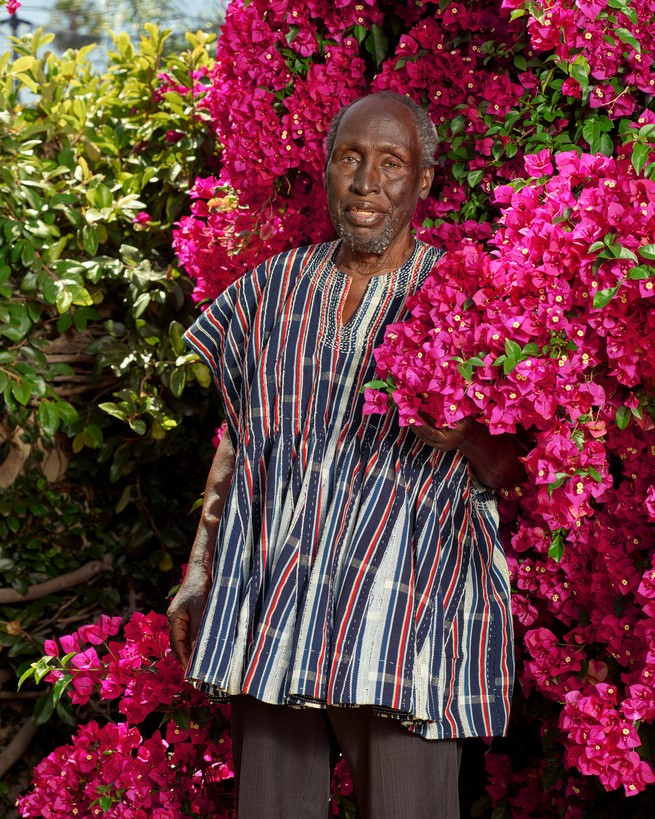 Author in African shirt standing in front of Flowers and shrubbery