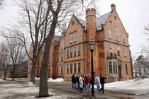 A photo of people walking by a Bowdoin, College campus building. 