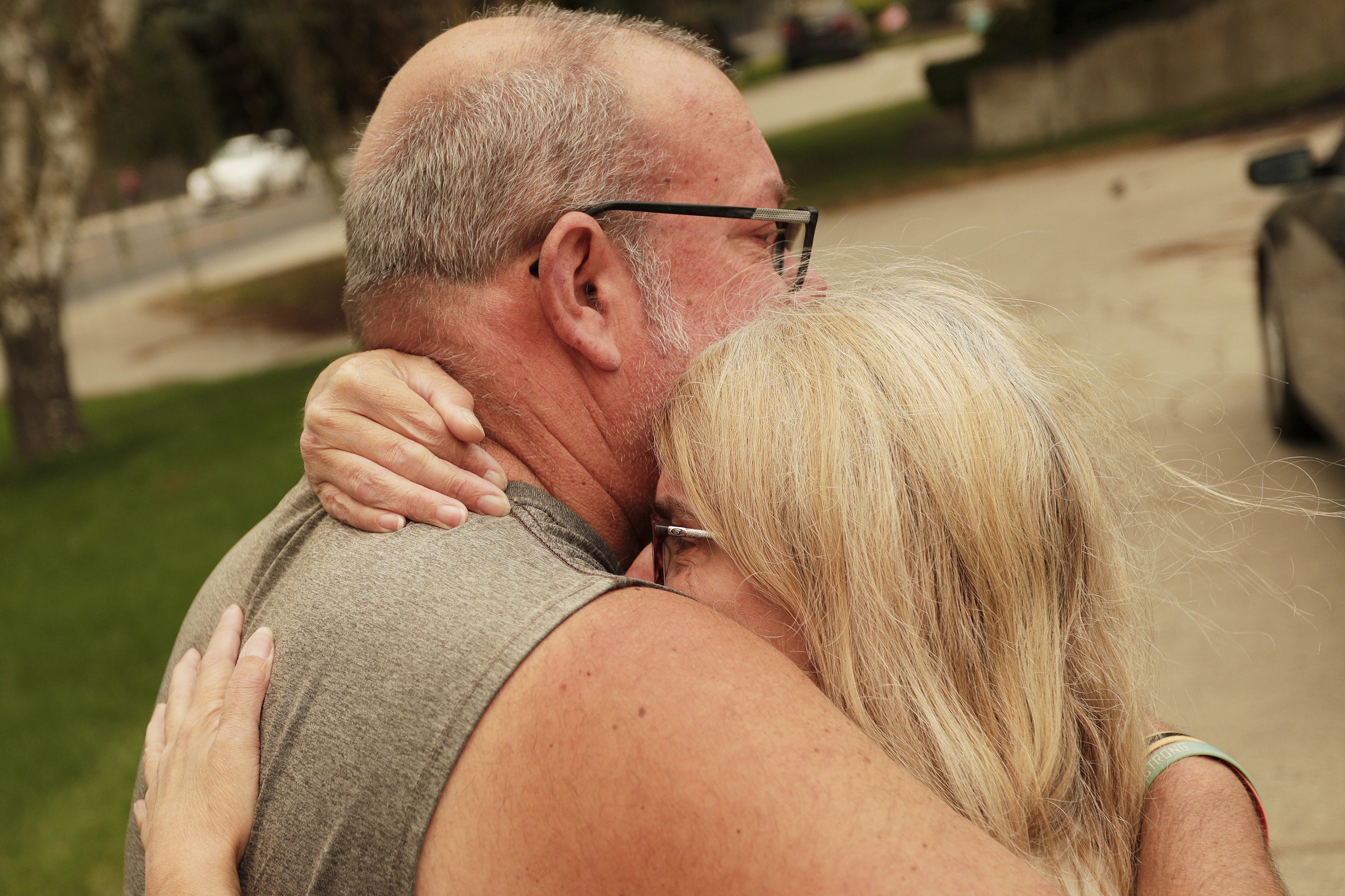 A couple embraces outside of a burned residence.