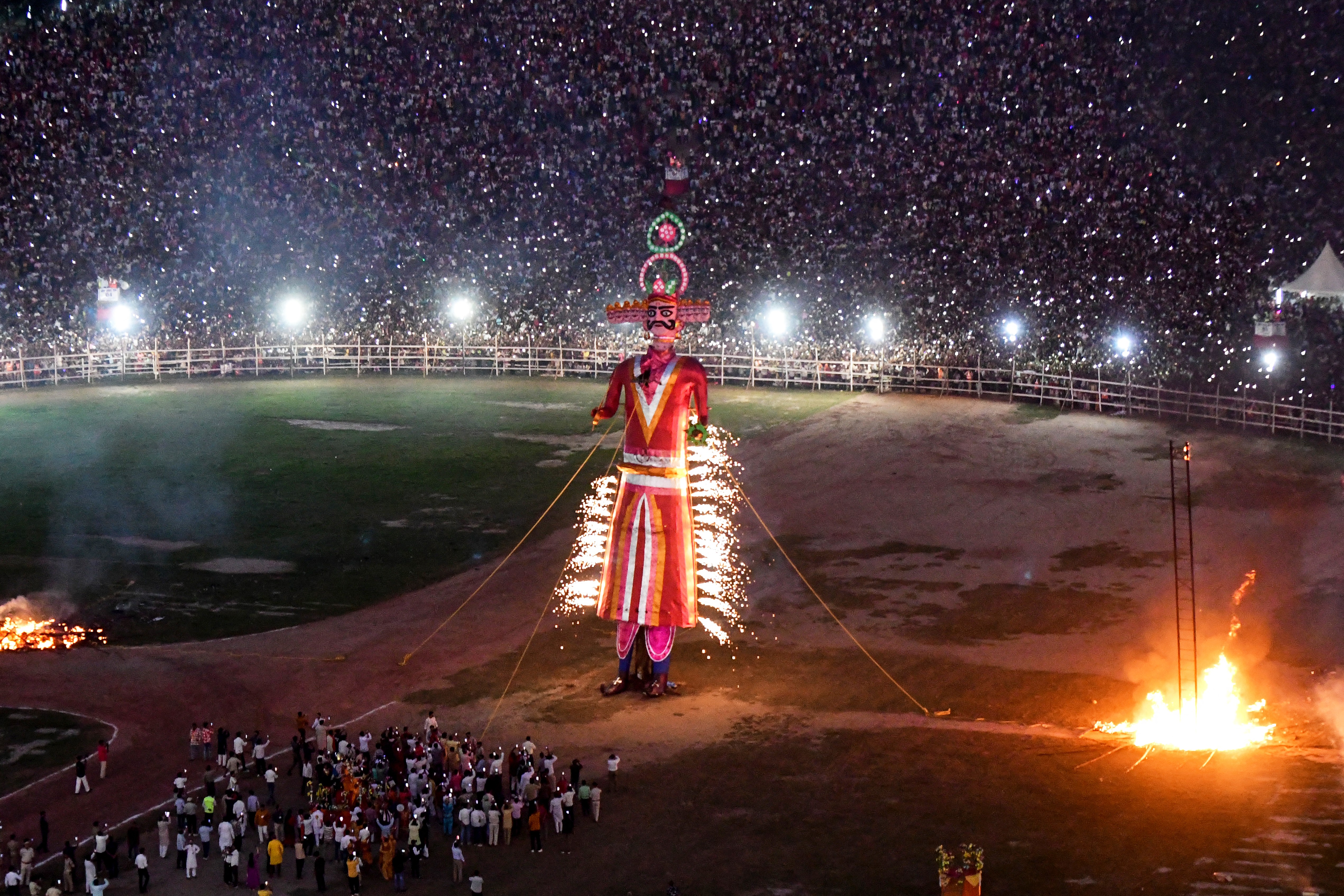 An effigy of a mythical demon king is set on fire in an arena full of spectators.