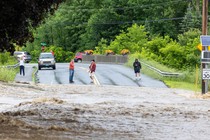 Onlookers inspect a flooded road in Southern Vermont